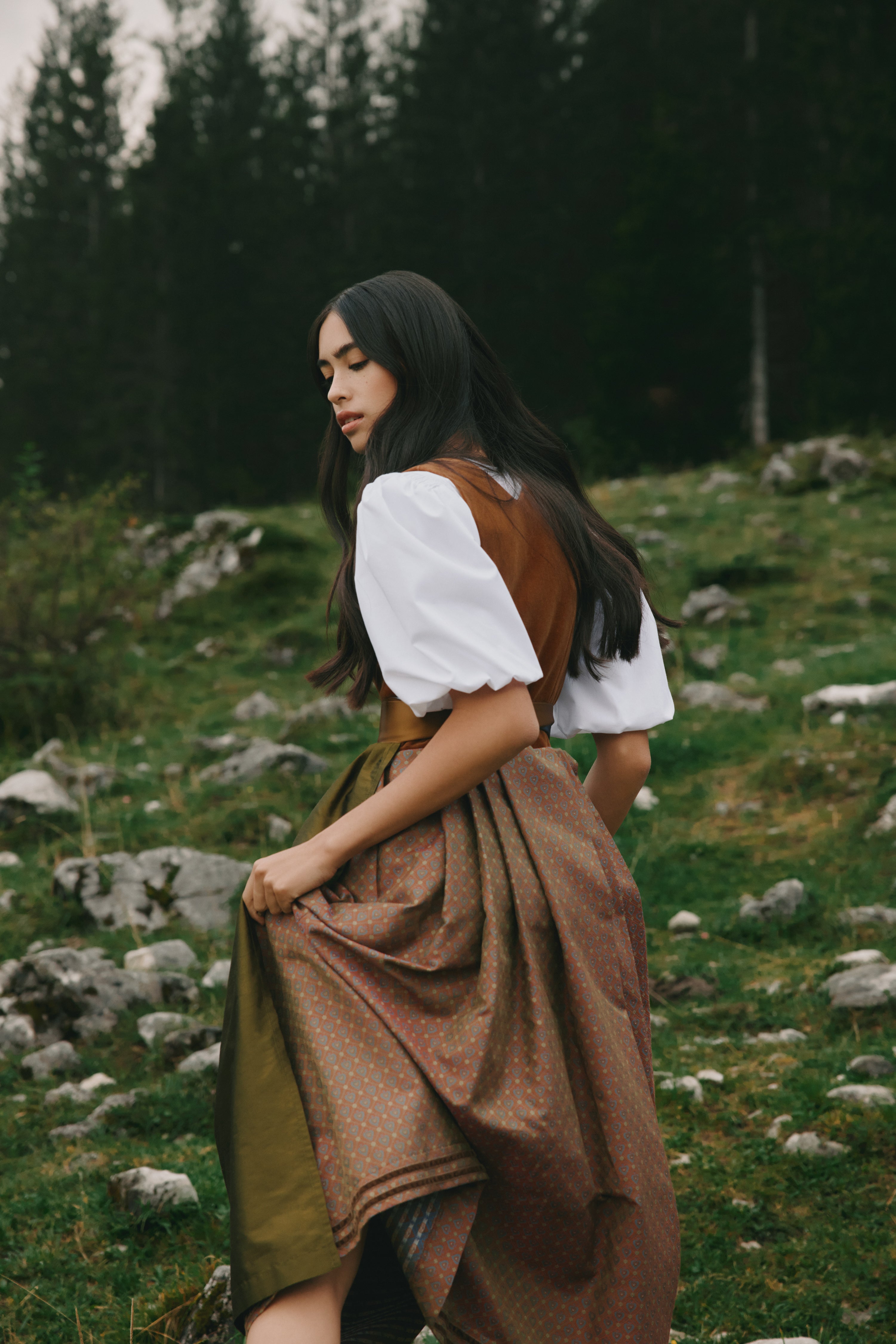 Frau im Dirndl geht durch eine Bergwiese