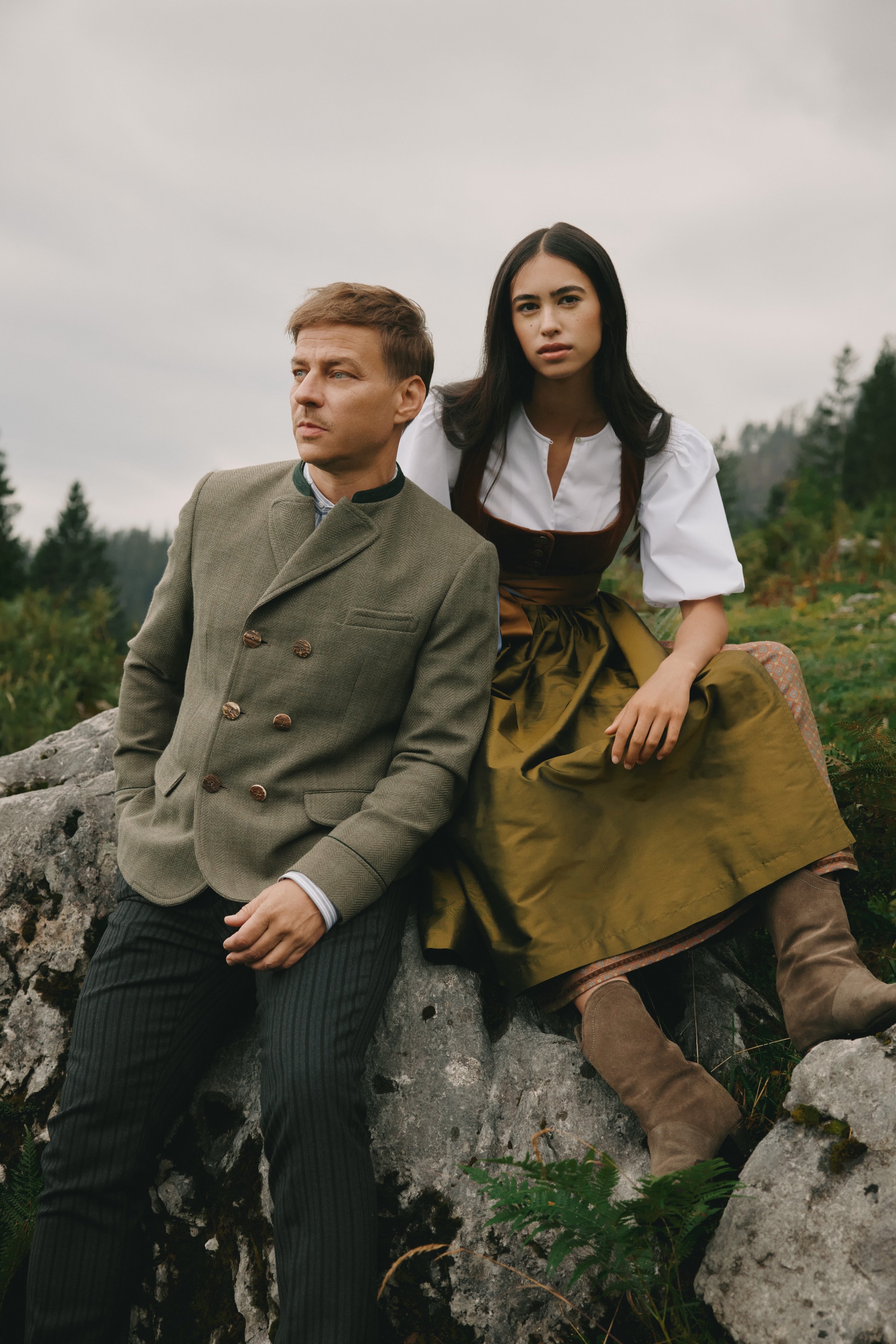 Paar in Tracht auf einem Felsen in den Alpen