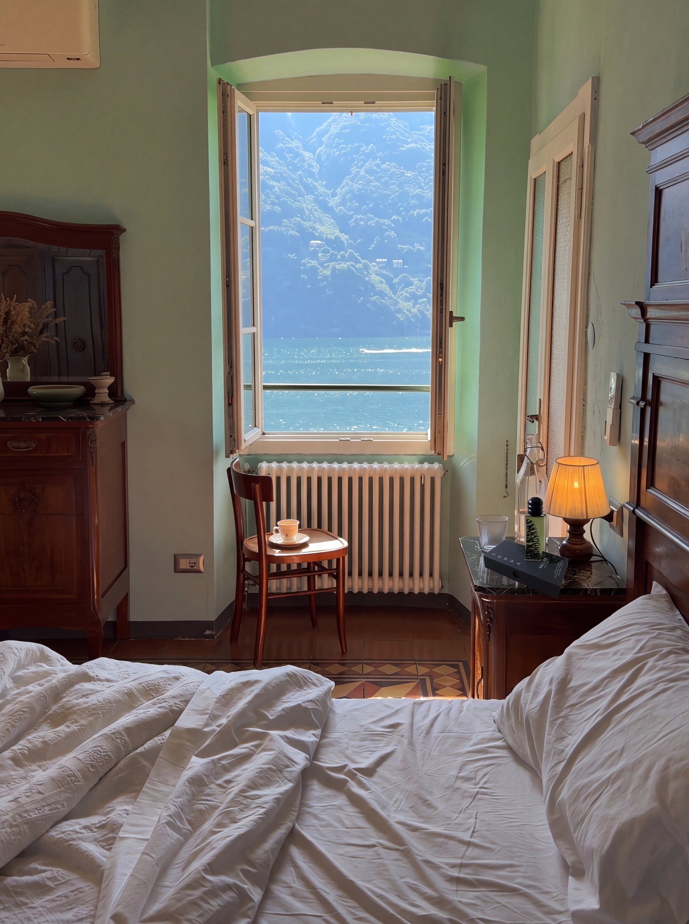 Zimmer mit offenem Fenster und Seeblick, TERRA auf dem Nachttisch